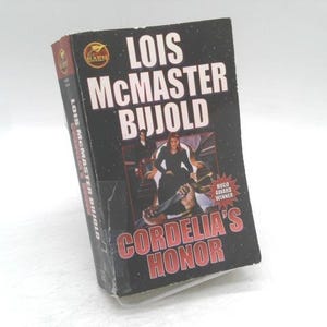 May include: A hardcover book titled "Cordelia's Honor" by Lois McMaster Bujold. The cover is black with white text and a central image of two people. The book has a "Hugo Award Winner" sticker.