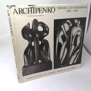 May include: A white hardcover book titled Archipenko Themes and Variations 1908-1963 by Donald Karshan. The cover features a black and white photograph of a dark abstract sculpture and a separate black and white graphic illustration of figures.