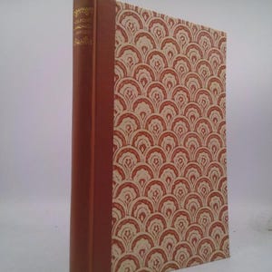 May include: A hardcover book with a patterned cover and a brown spine. The cover features a repeating fan-like design in cream and reddish-brown. The spine has gold lettering. The book is standing upright.