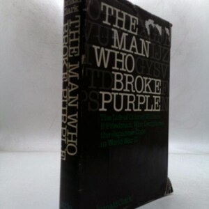 May include: A hardcover book titled "The Man Who Broke Purple" by Ronald Clark. The book has a black cover with white lettering. The spine reads "The Man Who Broke Purple" vertically. The book's subtitle is visible.