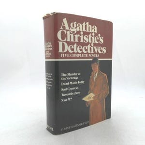 May include: A hardcover book titled "Agatha Christie's Detectives: Five Complete Novels." The book has a burgundy top and a black bottom. The cover features an illustration of a man in a coat holding a paper.
