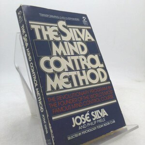 May include: A hardcover book titled "The Silva Mind Control Method" with a navy blue cover and white lettering. The book is by José Silva and Philip Miele. The book is displayed on a clear plastic stand.