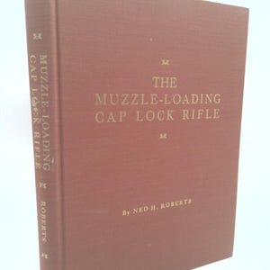 May include: A maroon hardcover book titled "The Muzzle-Loading Cap Lock Rifle" by Ned H. Roberts. The title and author's name are in gold lettering. The spine reads "Muzzle-Loading Cap Lock Rifle" and "Roberts".