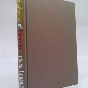 May include: A gray hardcover book with the title "A Smattering of Ignorance - OSCAR LEVANT" printed on the spine in white, yellow, and red lettering.