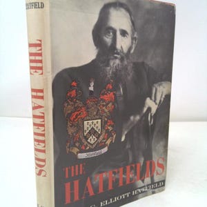 May include: A vintage book titled "The Hatfields" with a portrait of a man with a long beard on the cover. The book's spine displays the title vertically. The cover features a family crest and the author's name.