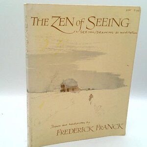 May include: A vintage book titled "The Zen of Seeing" with a beige cover. The cover features a watercolor illustration of a house on a snowy hill and a person walking. The author's name, Frederick Franck, is printed at the bottom.