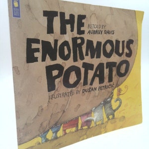 May include: The cover of a children's book titled "The Enormous Potato" retold by Aubrey Davis and illustrated by Dusan Petricic. The cover features a large brown potato with a yellow background and a group of small animals peeking out from under the potato.