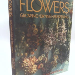 May include: A hardcover book titled "FLOWERS" with the subtitle "GROWING • DRYING • PRESERVING." The cover features a photograph of dried flowers in shades of brown, orange, and purple. The author's names are Alan Cormack and David Carter.
