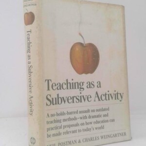 May include: A book titled "Teaching as a Subversive Activity" with a large apple illustration on the cover. The book's title is in large, bold letters, with the author's names at the bottom. The book is off-white with a slightly aged appearance.