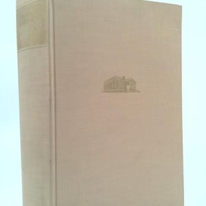 May include: A hardcover book with a beige cover and spine. The spine has gold lettering. The front cover features a small, embossed illustration of a building. The book is standing upright against a light blue background.