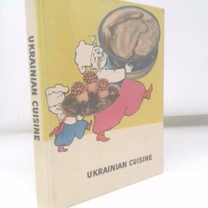 May include: A vintage cookbook titled "Ukrainian Cuisine" with a yellow cover. The cover features a cartoon illustration of two figures carrying food. The book's spine reads "Ukrainian Cuisine."