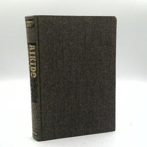 May include: A hardcover book with a dark gray textured cover. The spine features the title "Aikido" in gold lettering. The book appears to be in good condition, with a clean, minimalist aesthetic. The book is standing upright.