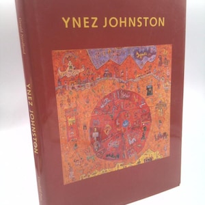 May include: A hardcover book titled "Ynez Johnston" with a reddish-brown cover. The cover features gold lettering and a colorful abstract painting. The spine reads "Ynez Johnston" vertically. The book is by Gerald Nordland.