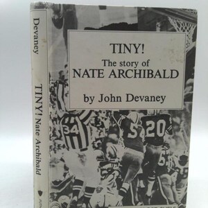 May include: A black and white photo of a basketball game on the cover of a book titled "TINY! The story of NATE ARCHIBALD by John Devaney". The book is part of the PUTNAM SPORT SHELF series.