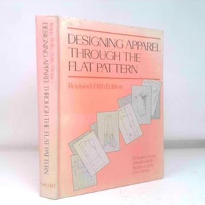 May include: A book titled "Designing Apparel Through the Flat Pattern" with a peach-colored cover. The book's title is in large, bold letters. The cover also features illustrations of garment patterns.