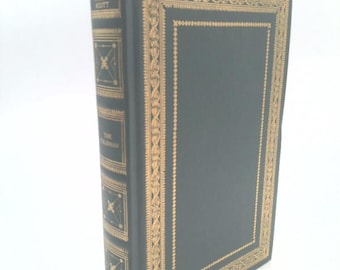 May include: A hardcover book with a dark green cover and gold decorative accents. The spine features the author's name, Sir Walter Scott, and the title, The Talisman. The edges of the cover are adorned with intricate gold patterns.