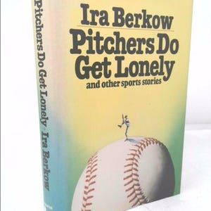 May include: A yellow book cover with the title "Pitchers Do Get Lonely" and the author "Ira Berkow". The cover features a baseball with a small figure of a baseball player standing on top of it.