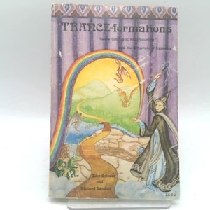 May include: A paperback book titled TRANCE-formations: Neuro-Linguistic Programming and the Structure of Hypnosis by John Grinder and Richard Bandler. The cover features a wizard-like figure, a rainbow, dragons, and a winding path in a landscape.