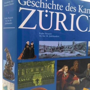 May include: A blue book titled "Geschichte des Kantons Zurich" with white text. The book features images of historical scenes and figures. The text "Frühe Neuzeit 16. bis 18. Jahrhundert" is also visible.