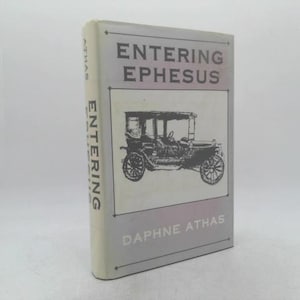 May include: A hardcover book titled "Entering Ephesus" by Daphne Athas. The cover features a black and white illustration of a vintage car. The book's spine displays the word "Entering" vertically.