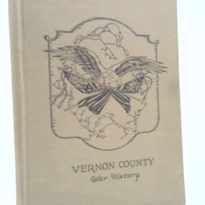 May include: A vintage book with a light tan cover. The cover features a detailed illustration of an eagle with outstretched wings, holding flags. The text "VERNON COUNTY War History" is printed below the illustration.