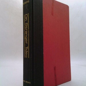 May include: A black and red hardcover book with the title "On Stranger Tides" by Powers on the spine. The book is part of the Ace Books series.