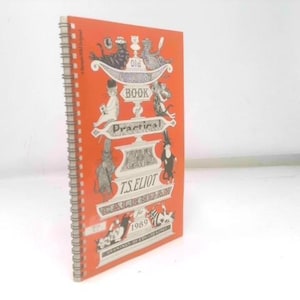 May include: An orange spiral-bound calendar titled "Old Possum's Book of Practical Cats Calendar for 1989" by T.S. Eliot. The cover features illustrations of cats and decorative text in white. The calendar is standing upright.