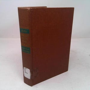 May include: A hardcover book with a brown cover and a green and white label on the spine. The book's title is visible on the spine. The book is standing upright on a white surface.