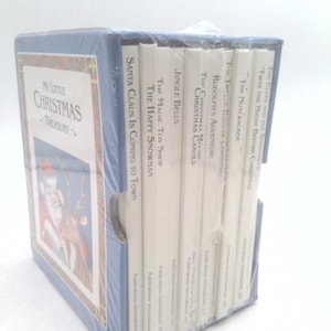 May include: A white ceramic mug with a black handle and the text "But First, Coffee" in a handwritten style. The mug is on a white surface. The mug is likely for hot beverages.