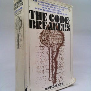 May include: A hardcover book titled "The Codebreakers" by David Kahn. The cover is off-white with black and brown text and graphics. The book's title is prominently displayed, with additional text describing the book's subject matter.