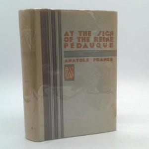 May include: A vintage book titled "At the Sign of the Reine Pedaque" by Anatole France. The book has a light tan cover with a vertical brown stripe and text in a serif font. The book is wrapped in clear plastic.