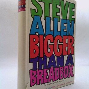 May include: A book cover with the title "STEVE ALLEN BIGGER THAN A BREADBOX" in colorful, oversized letters. The book is illustrated by Rowland B. Wilson and features a commentary by Leonard Feather.