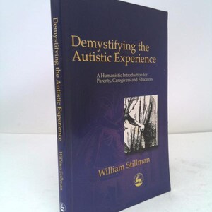 May include: A hardcover book titled "Demystifying the Autistic Experience" by William Stillman. The book has a dark blue cover with gold lettering and a black and white illustration. The spine also has the title.
