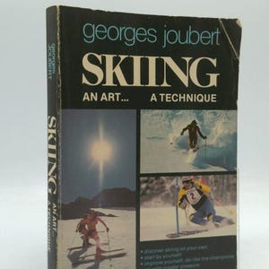 May include: A vintage book titled "SKIING" by Georges Joubert. The cover features skiers in action, a bright sun, and the text "AN ART... A TECHNIQUE." The book's spine also displays the title and author.