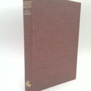 May include: A hardcover book with a textured, reddish-brown cover. The title "Malcolm Lowry's Volcano" and the author's name, David Markson, are printed vertically on the spine. The book is a vintage edition.