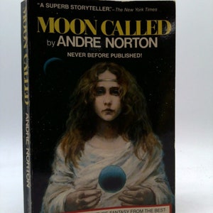 May include: A book cover with a black background and a young woman holding a blue orb. The title of the book is "Moon Called" by Andre Norton. The text "Never Before Published!" is also on the cover.