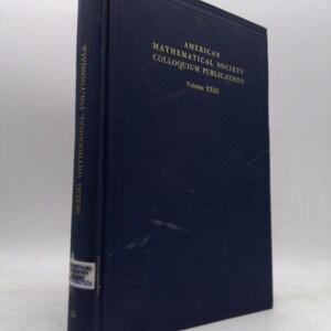 May include: A navy blue book titled "Szego, Orthogonal Polynomials" from the American Mathematical Society Colloquium Publications, Volume XXIII. The book has gold lettering and a small white label on the spine.