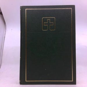 May include: A dark green book with a gold border and a gold cross emblem on the cover. The book is rectangular and appears to be closed, with a textured surface.