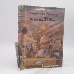 May include: A hardcover book titled "Footprints in the Wilderness: A History of The Lost Rhoades Mines." The cover features a vintage illustration of several men and mining equipment, with a sepia-toned color scheme.