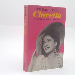 May include: A hardcover book titled "Claretta" by Roberto Gervaso. The cover is pink with the title in yellow and the author's name above. A black and white image of a woman wearing a large hat is featured on the cover.