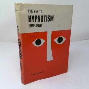May include: A hardcover book titled The Key to Hypnotism Simplified by James T. McVay. The cover features a white top section with black text and a large orange bottom section displaying two stylized black and white eyes and a nose graphic.