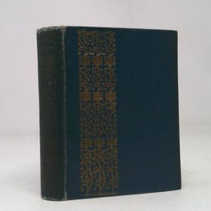 May include: A vintage book with a dark blue cover and a decorative gold floral pattern on the spine. The spine is a darker shade of green. The book is standing upright against a white background.