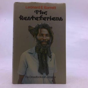 May include: Book cover featuring a portrait of a man with long dreadlocks and a beard. The title reads "The Rastafarians" by Leonard E. Barrett. The subtitle is "The Dreadlocks of Jamaica". The cover has a brown and tan color scheme.