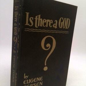 May include: A hardcover book titled "Is there a GOD" by Eugene Fersen. The book has a black cover with gold lettering and a large question mark. The title is also printed on the spine.