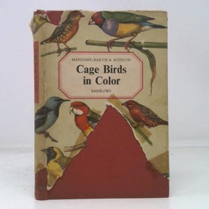 May include: Vintage book titled "Cage Birds in Color" by Mandal-Barth & Anthon. The cover features illustrations of colorful birds perched on branches. The book has a worn, aged appearance with a red and tan color scheme.