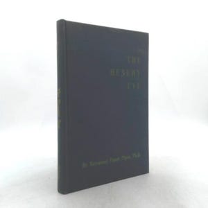 May include: A hardcover book titled "The Husky Eye" in dark blue with gold lettering. The book is standing upright, showcasing its spine and front cover. The author's name is visible at the bottom of the cover.
