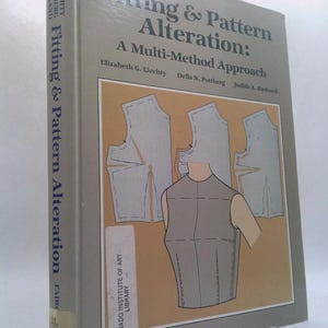 May include: A hardcover book titled "Fitting & Pattern Alteration: A Multi-Method Approach" by Liechty, Pottberg, and Rasband. The cover features a diagram of a torso and pattern pieces in shades of gray and tan.