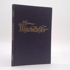 May include: A hardcover book titled The Windwalker with a dark purple cover and gold lettering. The title is printed in a stylized script on the front cover, while the spine displays the title, author name, and publisher in gold text.