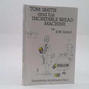 May include: A hardcover book titled "TOM SMITH and his INCREDIBLE BREAD MACHINE" by R.W. Grant. The cover features a cartoon illustration of a man, a bread machine, and text. Illustrations by Richard Stein.