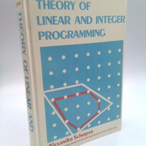 May include: A hardcover book titled "THEORY OF LINEAR AND INTEGER PROGRAMMING" by Alexander Schrijver. The book has a white cover with blue and red geometric designs and text. The book is part of the Wiley-Interscience series.